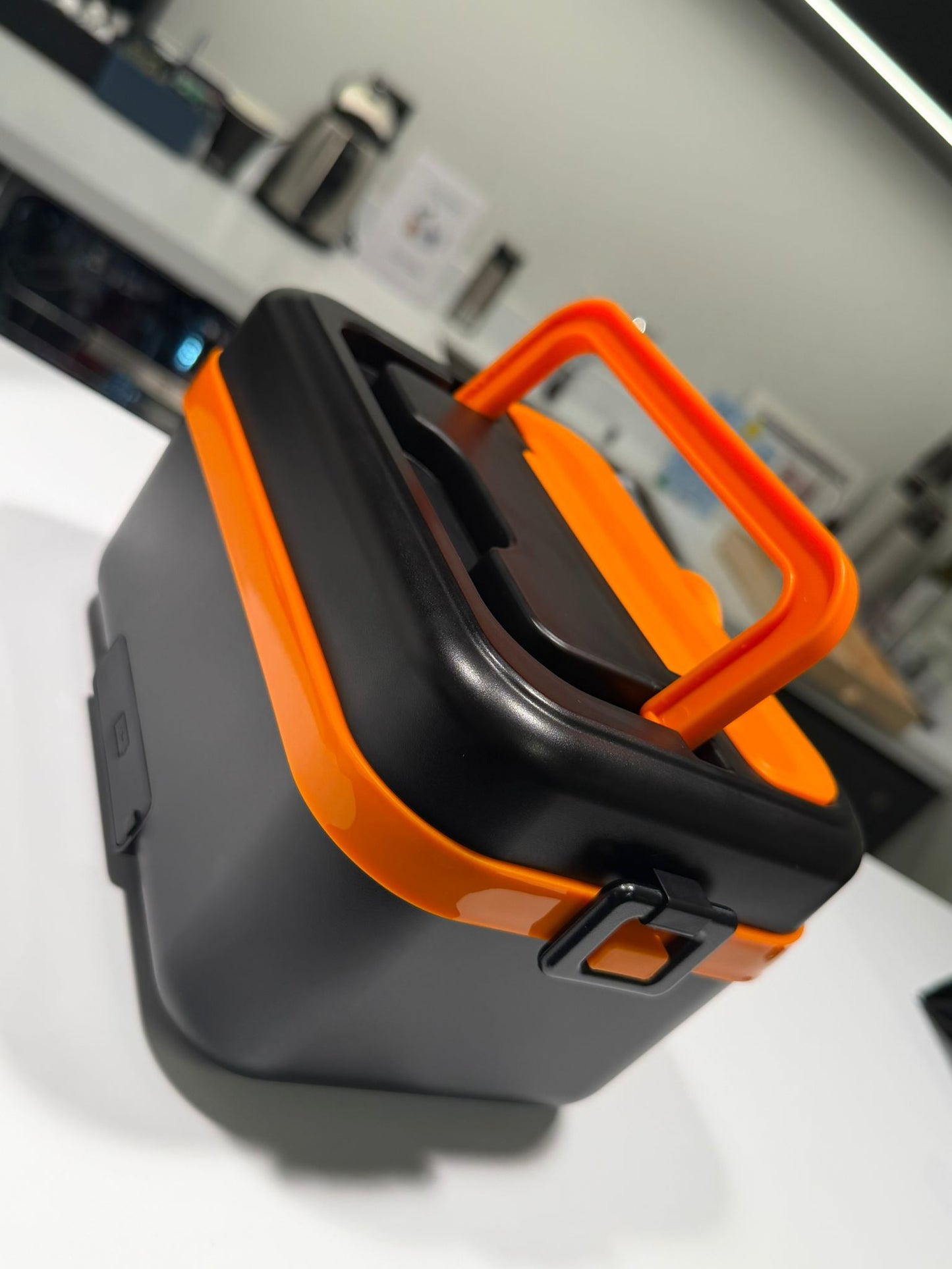 Black and orange tool box on a white surface with a blurred background