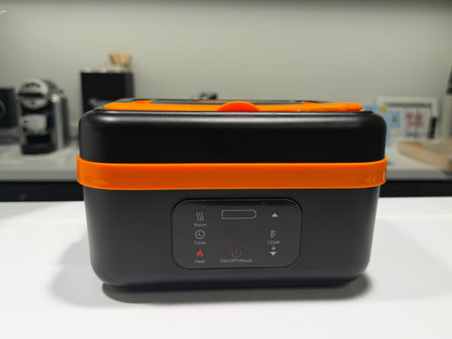 Black and orange portable device on a white surface with kitchen appliances in the background