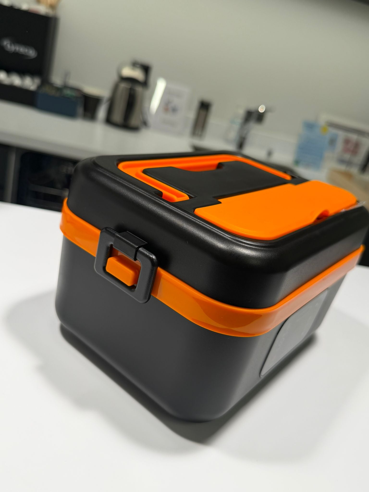 Black and orange toolbox on a white surface with a blurred background